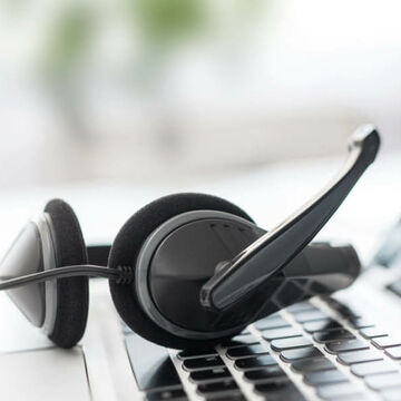 Ein Headset liegt auf der Tastatur eines Laptops